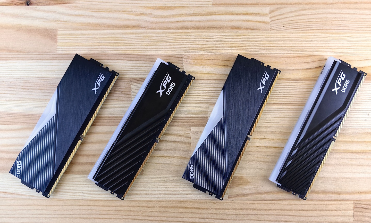 Das Bild zeigt vier DDR5-Arbeitsspeichermodule auf einer Holzoberfläche. Die Speicherriegel sind nebeneinander angeordnet und besitzen schwarze Kühlkörper. Das Bild zeigt vier DDR5-Arbeitsspeichermodule auf einer Holzoberfläche. Die Speicherriegel sind nebeneinander angeordnet und besitzen schwarze Kühlkörper.